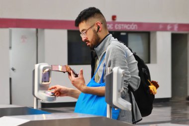 29 Ekim 2023 'te Mexico City, Meksika' da bir yolcu Pantitln 'den sonra Metro Hattı 1' in yeniden açılması sırasında Mexico City Metro 'daki kart okuyucularına ulaşmak için Entegre Mobilite kartına ulaşır.