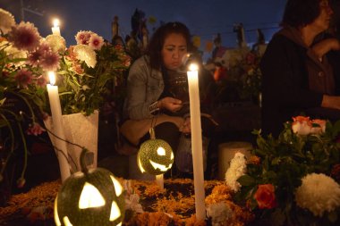 2 Kasım 2023, Mexico City, Meksika: Akrabalar, Ölüler Günü kutlamaları sırasında mezarları cempasuchil çiçekleriyle süsler ve sevdiklerinin mezarlarını mumlarla aydınlatır, panteonu renk ve folklorla doldururlar.