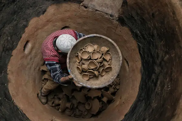11月0223日 インドのスリナガル カシミール カシミール ムスリム陶器のアブドゥル サラーム クマールが シュリナガルの郊外にあるディワール フェスティバルの前に自宅のワークショップでオーブンから土のランプを取り出します — ストック写真