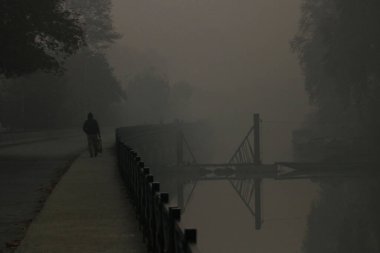 23 Kasım 2023, Srinagar Kashmir, Hindistan: İnsanlar Srinagar 'da sisli bir sabahta yol boyunca yürüyorlar. Kaşmir sisli ve soğuk hava koşullarına tanık olurken, Srinagar mevsimin en soğuk gecesini eksi 1,8 derece santigrat derecede kaydetti.