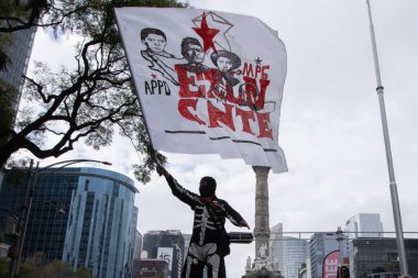 15 Aralık 2023 Mexico City, Meksika. Reforma Bulvarı 'ndaki Ulusal Eğitim İşçileri Koordinatörü' nün eğitim sisteminde iyileştirme ve daha iyi maaş talebi üzerine düzenlediği gösteri sırasında kapüşonlu bir kişi bayrak sallıyor.