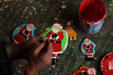 16 Aralık 2023, Srinagar Kashmir, Hindistan: Bir Kaşmir sanatçısı Srinagar 'daki Noel kutlamaları öncesinde atölyedeki Noel hediyelerini boyuyor