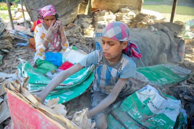 19 Aralık 2023 Sylhet-Bangladeş: Bangladeş 'in Sylhet kentindeki Surma Nehri' nin yanındaki çimento çuvallarında çalışarak ailesi için fazladan para kazanmak için çalışan bir çocuk hayatını riske atıyor