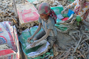 19 Aralık 2023 Sylhet-Bangladeş: Bangladeş 'in Sylhet kentindeki Surma Nehri' nin yanındaki çimento çuvallarında çalışarak ailesi için fazladan para kazanmak için çalışan bir çocuk hayatını riske atıyor