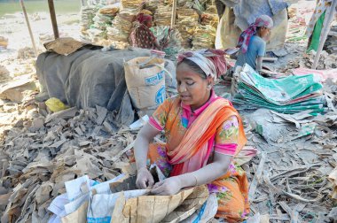 19 Aralık 2023 Sylhet-Bangladeş: Bangladeş 'in Sylhet kentindeki Surma Nehri' nin yanındaki çimento çuvallarında çalışarak ailesi için fazladan para kazanmak için çalışan bir çocuk hayatını riske atıyor