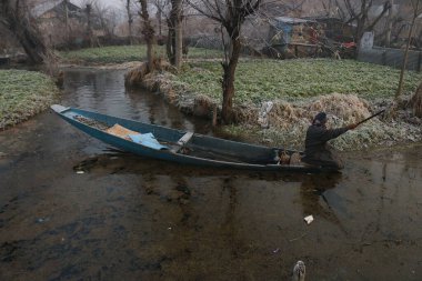 21 Aralık 2023, Srinagar Kashmir, Hindistan: Bir adam Srinagar 'daki Dal Gölü' nün iç kesimindeki kısmen donmuş suda kürek çekiyor. En sert 40 günlük kış dönemi olan Chillai-Kalan, Perşembe günü Kaşmir 'de başlıyor.