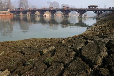 January 15,2024, Srinagar Kashmir, India : View of a dried portion of the Jhelum river in Srinagar. Prolonged Dry Winter Spell Leaves Jhelum River at Historic Low, Jeopardizing Houseboats and Disappointing Skiers in Gulmarg.  clipart