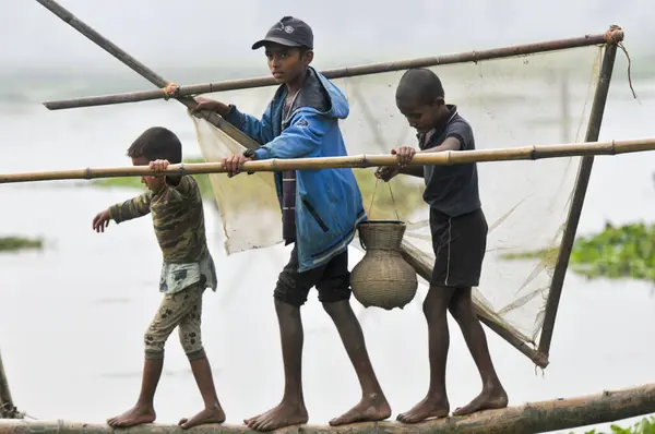stock image 15 January 2024 -Bangladesh: Children fishing with Bamboo fish trap at the Beel. While Rural people armed with Bamboo fish traps and handmade fishing net to take parts to celebrating in a 100 years winter polo bawa fishing festival at the Gowahori 