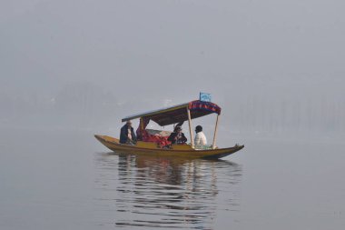 January 16, 2024, Srinagar, India: Non local people riding in a shikara at kashmir's famous tourist destination Dallake srinagar in a cold winter day. on January 16, 2024, Srinagar, India.  clipart