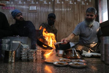 18 Ocak 2024, Srinagar Kashmir, Hindistan: Srinagar 'da soğuk bir sabahta müşterilere servis yapmak için Harissa' nın bulunduğu tabaklara sıcak yağ döken bir şef. Harissa, Kashmir 'de kış aylarında hazırlanmış eşsiz bir koyun eti tarifidir..