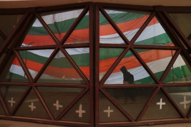 23 Ocak 2024, Srinagar Kashmir, Hindistan: Bir adam Srinagar 'da dev bir Hint üçlü renginin yanından geçerken aynanın içinden görülüyor
