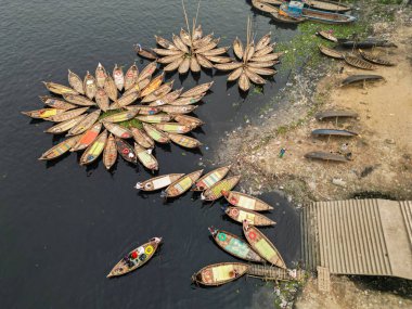 30 Ocak 2024, Dhaka, Bangladeş: Buriganga Nehri limanındaki ahşap yolcu teknelerinin havadan görünüşü. Renkli desenli halılarla süslenmiş tekneler, şehrin varoşlarındaki işçileri işlerine götürüyorlar.