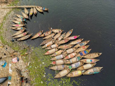 30 Ocak 2024, Dhaka, Bangladeş: Buriganga Nehri limanındaki ahşap yolcu teknelerinin havadan görünüşü. Renkli desenli halılarla süslenmiş tekneler, şehrin varoşlarındaki işçileri işlerine götürüyorlar.