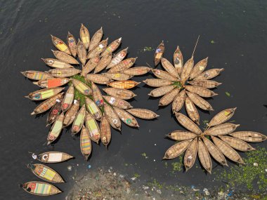 30 Ocak 2024, Dhaka, Bangladeş: Buriganga Nehri limanındaki ahşap yolcu teknelerinin havadan görünüşü. Renkli desenli halılarla süslenmiş tekneler, şehrin varoşlarındaki işçileri işlerine götürüyorlar.