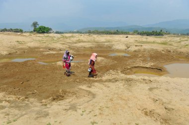5 Mart 2024, Sylhet, Bangladeş: İki ev hanımı, Bholaganj 'ın Kalairag bölgesinde Companiganj upazila sınırındaki neredeyse kuru bir rezervuardan ev kullanımı için su topluyor
