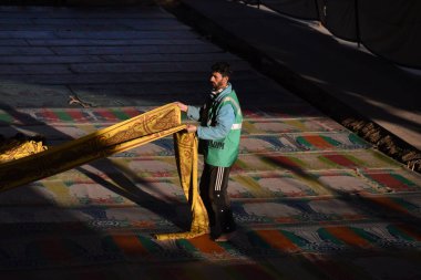 19 Mart 2024, Srinagar, Hindistan: Bir adam kutsal Ramazan ayında bir caminin önündeki yemek örtüsünü düzeltiyor