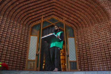 19 Mart 2024, Srinagar, Hindistan: Bir adam kutsal Ramazan ayında bir caminin önünde içi dolu yiyecek dolu bir sepet taşıyor