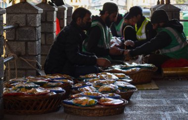 19 Mart 2024, Srinagar, Hindistan: Kaşmir Müslümanları kutsal Ramazan ayında bir caminin önünde, insanlar için yemek hazırlıyorlar.