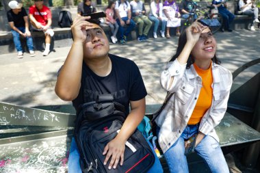 9 Nisan 2024, Mexico City, Mexico City: Bağımsızlık Meleği 'nin çevresinde toplanan insanlar, güneşin kısmi tutulmasını gözlemlemek için özel lensler kullandılar.