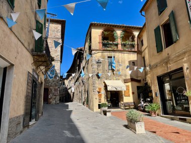 SARTEANO, İtalya - 7.08.2023: Siena ilindeki Sarteano Toskana bölgesinde mağazalar ve restoranlar. Yüksek kalite fotoğraf. Şehir bayraklarla süslenmiş. Panjurlu eski evler.