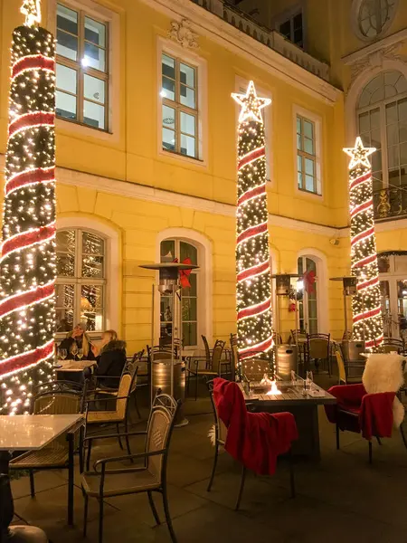 DRESDEN, GERMANY - 27.12.2018: An indoor Christmas courtyard at the hotel. People are sitting at tables outside. The yard is decorated with Christmas ornaments and stars. A fire is burning.