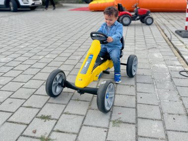 Parkta oynayan ve sarı araba kullanan sevimli küçük çocuk.. 