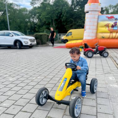 Parkta oynayan ve sarı araba kullanan sevimli küçük çocuk.. 