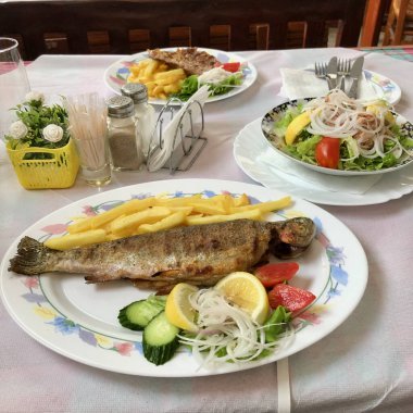 Balkan mutfağı. Ochrid Gölü 'nden ızgara balık, sebze, limon ve patates dilimleri. Geleneksel öğle yemeği. Yüksek kalite fotoğraf