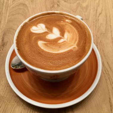 Cappucino kahve fincanı ahşap masada. Romantik çiçek deseni. Yüksek kalite fotoğraf