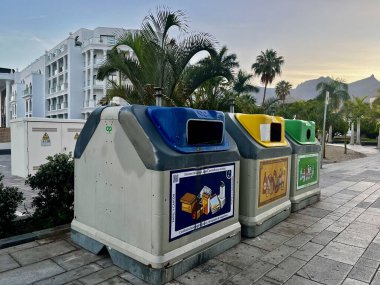 Costa Adeje, İspanya - 05.05.2024: Ayrı atık toplama için büyük çöp kutuları. Arka planda palmiye ağacı. Yüksek kalite fotoğraf