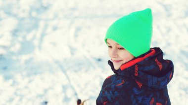Kış parkında eli kırık bir çocuk. Kırık kollu ve alçıtaşı kızakta oturan sevimli çocuk. Alçılı yaramaz çocuk..