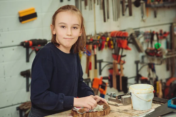 stock image Artisan boy is putting a protective mordant on the wood. Cute boy makes wooden clock in the workshop. Young carpenter working with wood in craft workshop. School, development and learning concept.