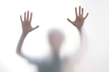 Silüet korkmuş çocuk cam kapının arkasında duruyor. Çocuk iki elini birden gösteriyor. Geçmişi tehlikeli, korku, yardım, musallat olma, korku ve paniği temsil ediyor. Gençlik sorunları, olumsuz duygular kavramı.