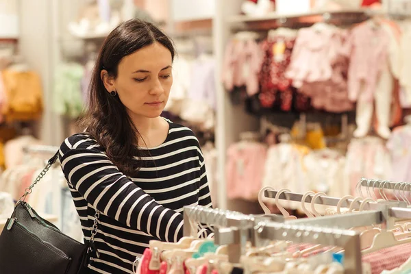 怀孕妇女为她未来的女儿选择衣服 妈妈在婴儿商店里购物 婴儿时尚 购物时间 销售和怀孕概念 — 图库照片