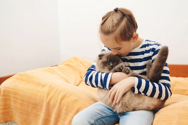 Happy kid hugging his cat. Boy relaxing on the bed with pet. Childhood, true friendship and home pet. Cute boy plays with a cat at home.