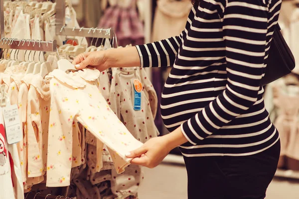 怀孕妇女为她未来的女儿选择衣服 妈妈在婴儿商店里购物 婴儿时尚 购物时间 销售和怀孕概念 — 图库照片