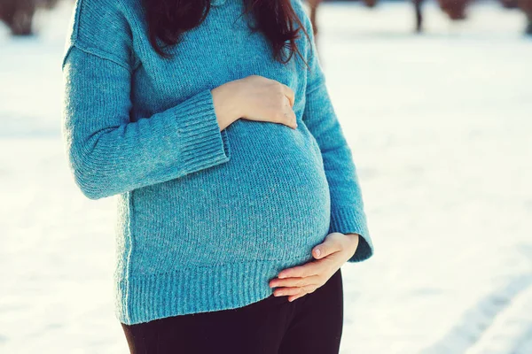 妊娠中の女性の腹冬の背景に 手で大きな腹に触れる青いセーターの妊婦さん 寒い気候で暖かい服 妊娠時間 赤ちゃんの期待 — ストック写真