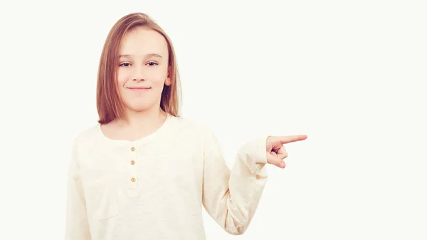 stock image Young teen boy with long hair posing at studio. Guy showing aside at empty space. Emotional portrait of happy teen boy over white background. Kid pointing at copy space.