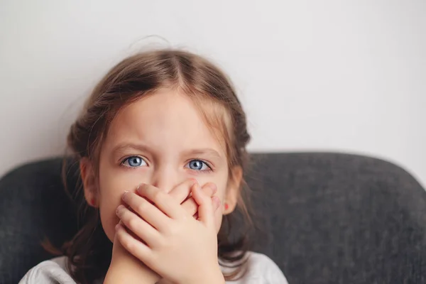 小女孩用手捂住嘴 伤心的小女孩坐在家里的沙发上 虐待儿童 家庭问题 — 图库照片