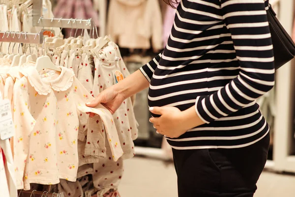 孕妇在服装店选择衣服和紧身衣 妈妈在婴儿商店里购物 婴儿时尚 购物时间 销售和怀孕概念 — 图库照片