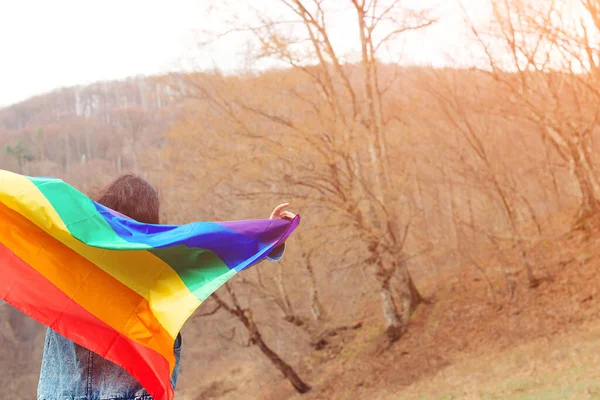 Celebrating the lgbt lesbian women rights. Woman holding the rainbow flag on the nature. Happiness, freedom and love concept for same sex couples. Lifestyle, people and love.