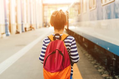 Çocuk tren istasyonunda ekspres tren bekliyor. Metroda sırt çantalı bir çocuk. Seyahat, turizm, tatil ve aile kavramı.