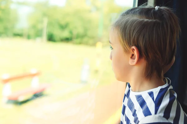 可怜的孩子从火车车窗往外看 这孩子坐火车旅行 小男孩正在乘火车旅行 悲伤和孤独 — 图库照片
