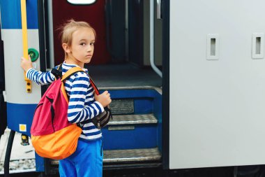 Çocuk tren istasyonunda ekspres tren bekliyor. Metroda sırt çantalı bir çocuk. Seyahat, turizm, tatil ve aile kavramı.