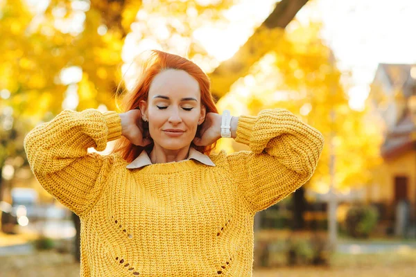 Redhead woman enjoying life outdoors. Happy woman walking in autumn park. Autumn fashion, lifestyle and holidays. Happy female outdoors portrait.