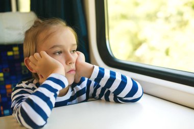 Küçük çocuk trende seyahat ediyor. Çocuk trenle seyahat ediyor. Trenin penceresinden bakan sevimli bir çocuk. Çocukluk, aile tatili, yaşam tarzı..