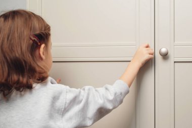 Küçük kız dolabı açıyor. Tahta bir dolapla oynayan tatlı bir kız bebek. Bebek evde oturma odasındaki dolabın kapısını açıyor. Küçük bir çocuk raf çekmecesini açıyor..