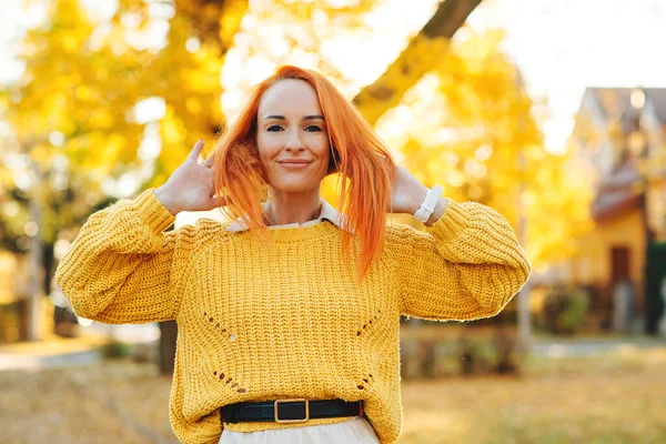 Redhead woman enjoying life outdoors. Happy woman walking in autumn park. Autumn fashion, lifestyle and holidays. Happy female outdoors portrait.