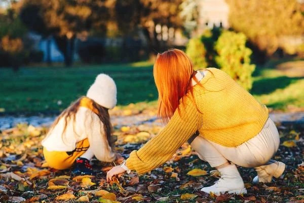 Lovely family laughing on autumn walk. Autumn holidays, lifestyle. Happy little girl and her mother playing in the autumn park.