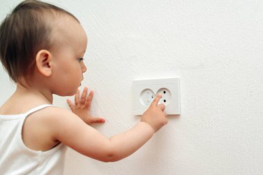 Çocuk parmağını sokete soktu. Bebek güç prizine dokunuyor. Bebek ve çocuk güvenliği kavramı. Meraklı küçük çocuk elektrik priziyle oynuyor.